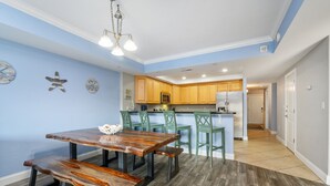 Una cocina moderna con armarios de madera, una isla central y un comedor con mesa y bancos de madera.
