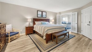 Une chambre à coucher comprenant un lit, des tables de chevet, un banc, une commode et une chaise.