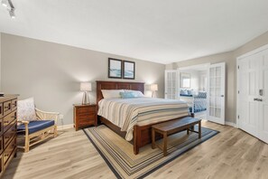 Een slaapkamer met een bed, nachtkastjes, een bankje, een dressoir en een stoel.