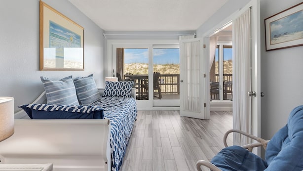 Une chambre à coucher avec un lit, une chaise, une porte donnant sur un balcon et un tableau accroché au mur.