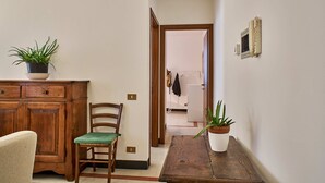 Un pasillo con una silla de madera, una mesita y dos plantas en macetas.