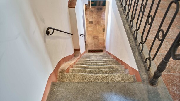 Una escalera con barandilla y una lámpara en la pared.