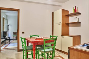 A compact kitchen with a dining table, chairs, and a refrigerator.