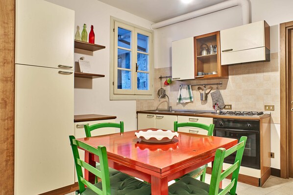 A kitchen with a dining table, chairs, a stove, oven, and cabinets.