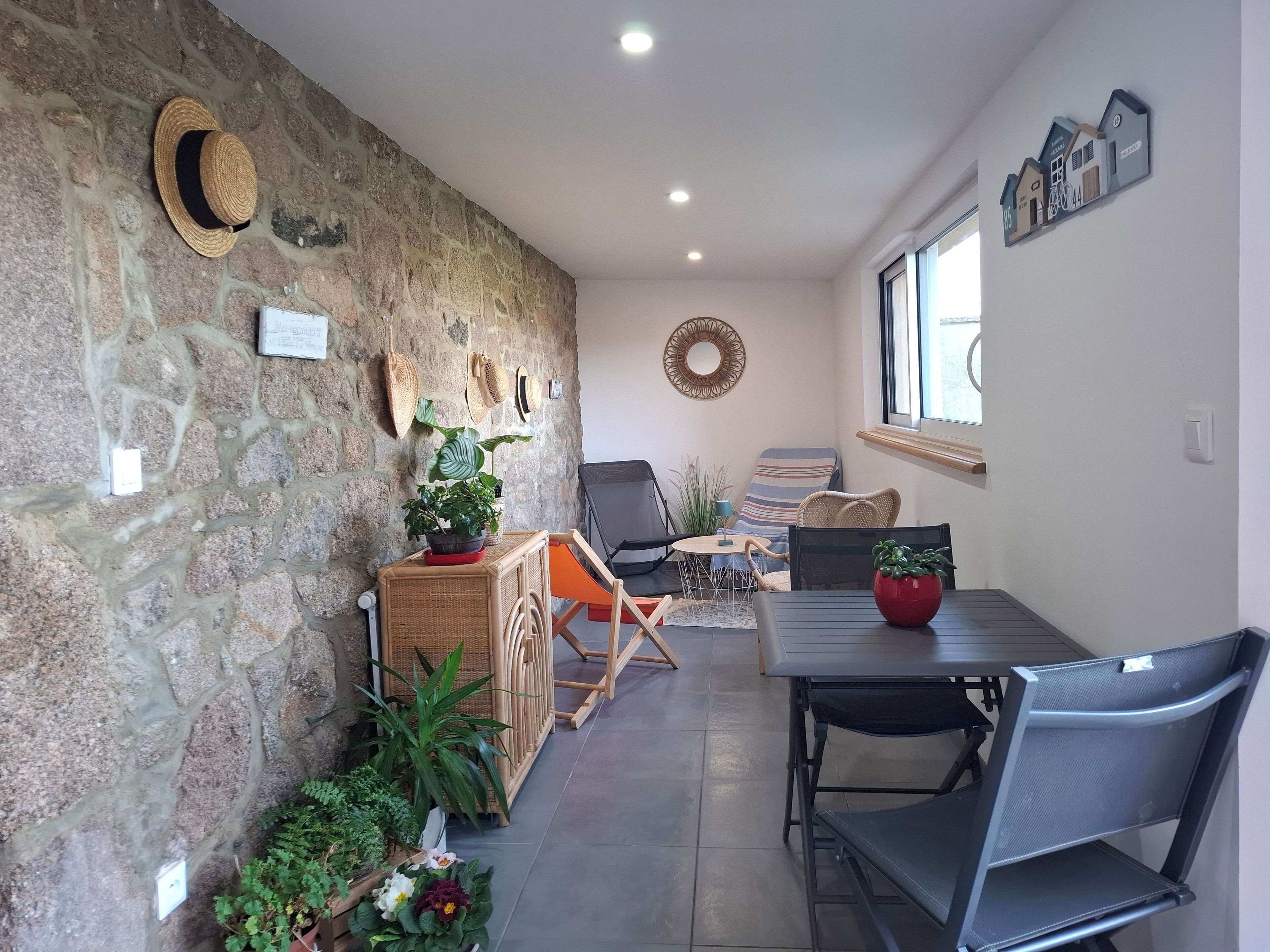 A cozy room with a stone wall, wicker furniture, and a dining table.