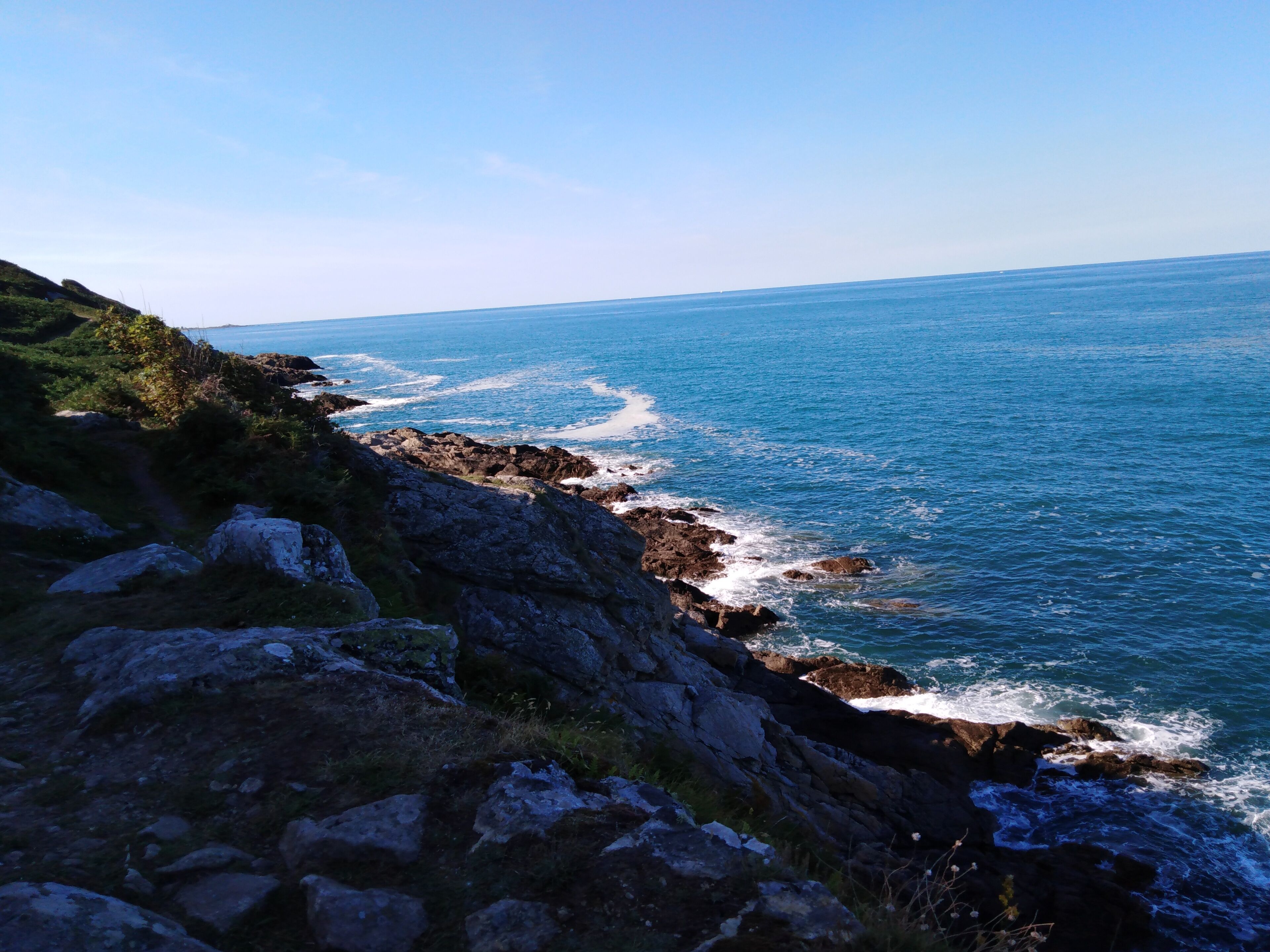 A coastal landscape with rocky terrain and the ocean.