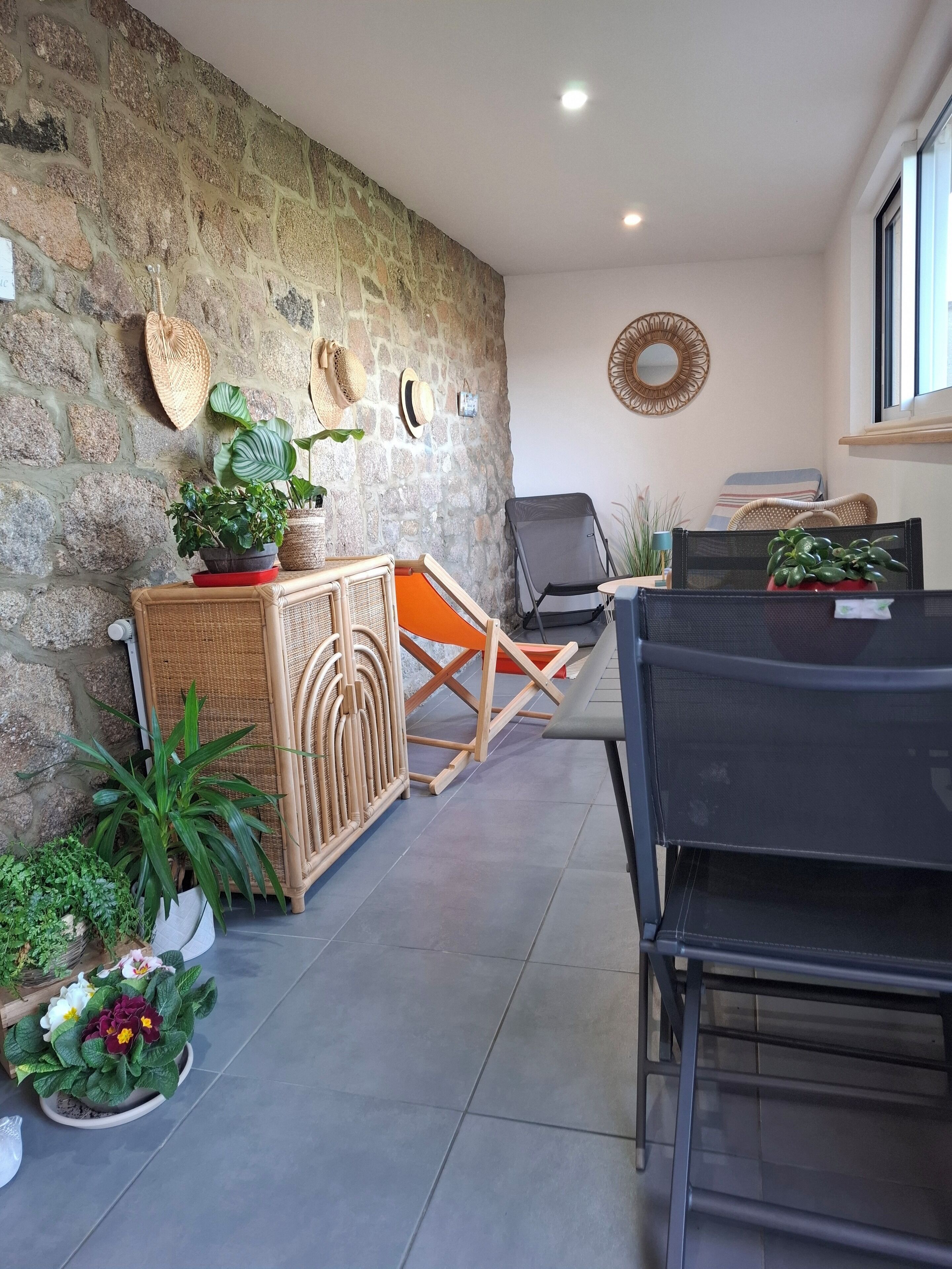 Ein Zimmer mit Steinwand, Korbmöbeln und Topfpflanzen.