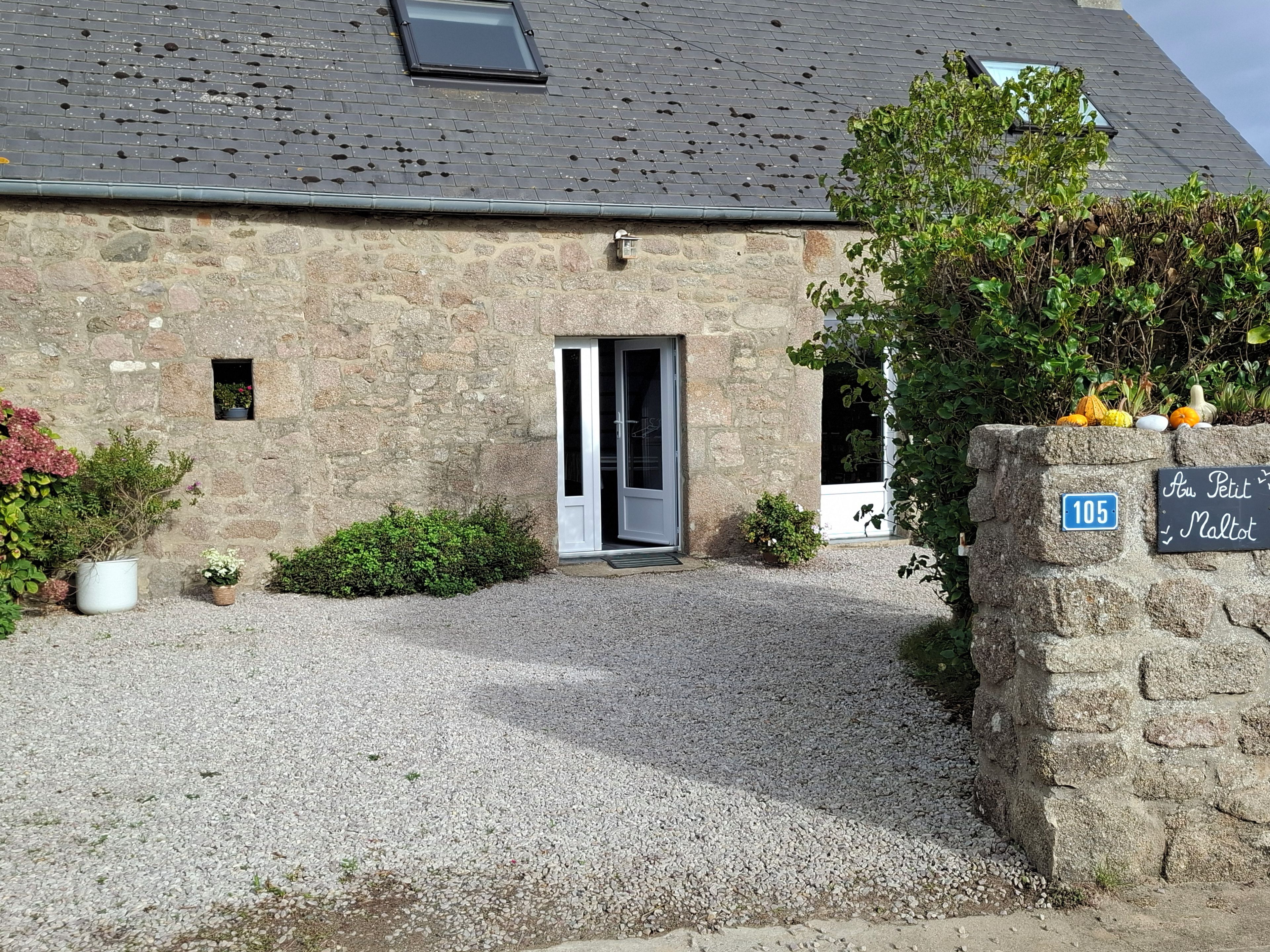 A stone building with a gravel driveway, a small door, and a sign indicating the address.