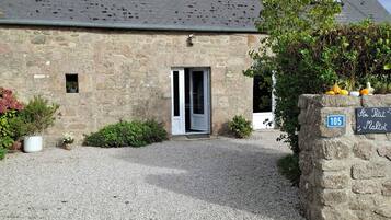 A stone building with a gravel driveway, a small door, and a sign indicating the address.
