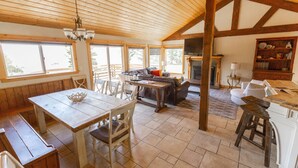 Una cocina amplia con vigas de madera, un comedor con mesa y sillas, y una chimenea.