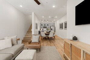 A modern living room with a sofa, a coffee table, and a dining area with chairs and a table. - Red Rock Oasis: Desert Color Lagoon + Beaches (St. George)