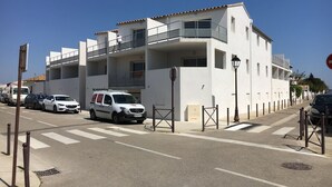 A multi-story building with balconies, a white facade, and a gated entrance. - Apartment T2 air-conditioned - Beach - Downtown (Saintes-Maries-de-la-Mer)