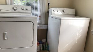 A laundry room with a front-loading washer and dryer, a window with blinds, and a power outlet on the wall. - Lovely 3bdrm home walking distance from Masters (Augusta)