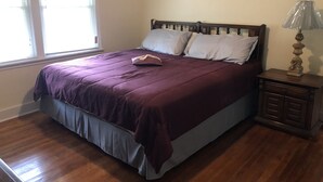 A bedroom with a wooden bed, a nightstand, and a window with blinds. - Lovely 3bdrm home walking distance from Masters (Augusta)