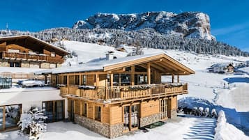 Una cabaña de madera con balcón, rodeada de montañas nevadas.