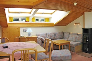 A cozy room with a wooden ceiling, a sofa, a table, and a fireplace.