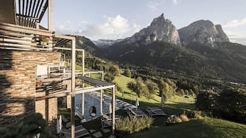 Un refugio de montaña con piscina, zona de estar al aire libre y vistas de las montañas circundantes.