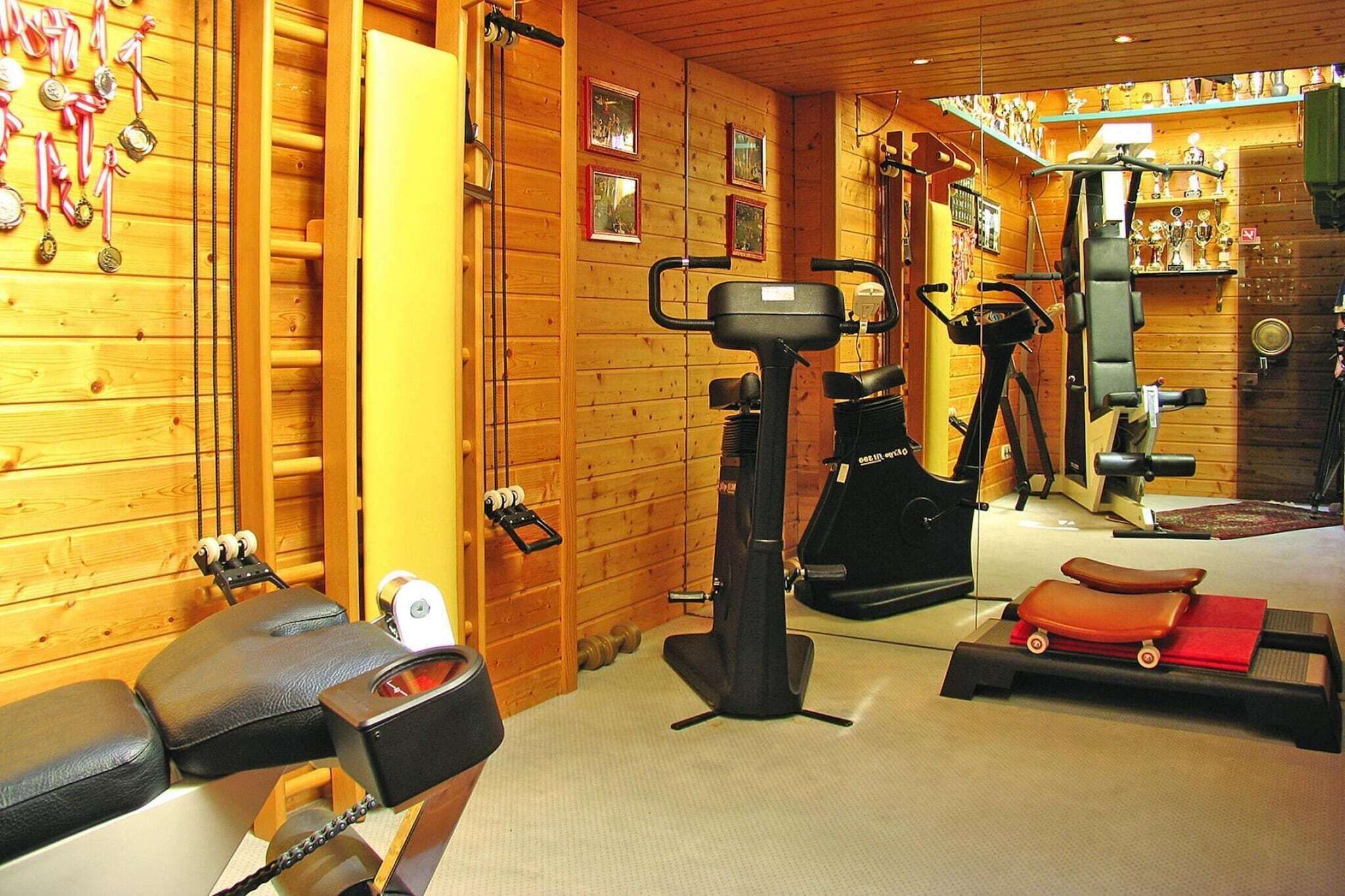 Un gimnasio con equipo de ejercicio, paredes de madera y trofeos.