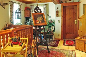 Un salon chaleureux avec un banc en bois, une petite table, un cheval à bascule et un tableau posé sur un chevalet.