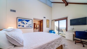 Une chambre d’hôtel avec un grand lit, un bureau avec une chaise, une télévision et un balcon avec vue.