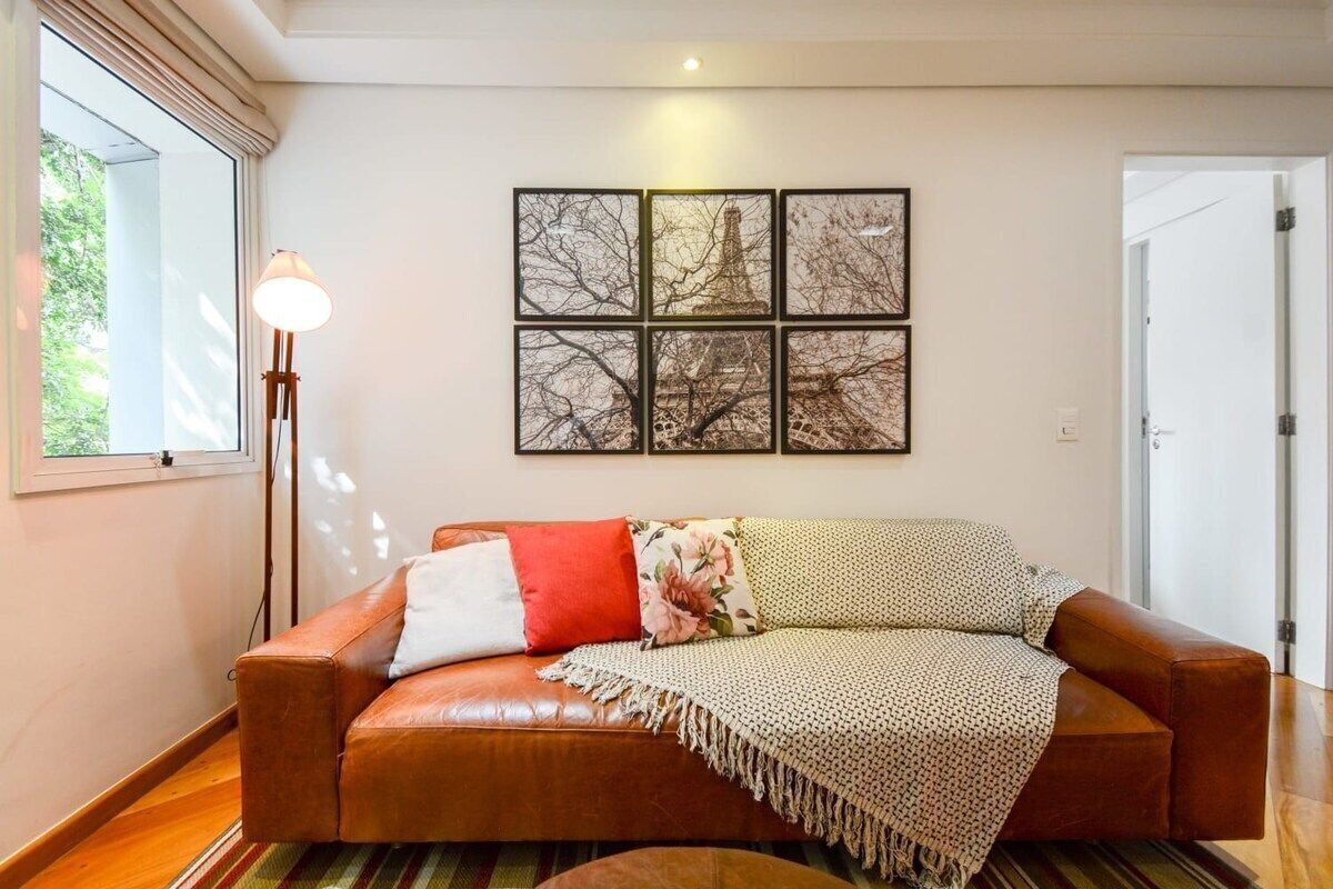 Ein Wohnzimmer mit braunem Ledersofa, einer Lampe und einem Wandbild mit dem Eiffelturm.