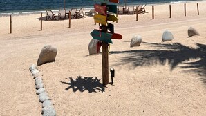 Een strand met een bord waarop afstanden naar verschillende landen staan aangegeven.