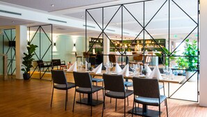 Een moderne eetruimte met een houten vloer, zwarte stoelen en een bar op de achtergrond.
