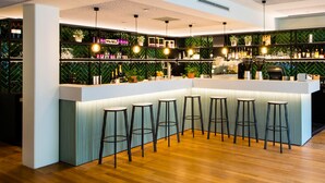 Een moderne barruimte met houten vloer, barstoelen en planken vol flessen en glazen.