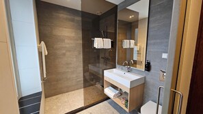 A modern bathroom with a glass-enclosed shower, a white sink, and a large mirror.