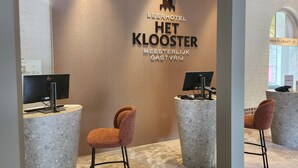 Een receptie met een modern design, met twee computerwerkplekken en een zithoek met een bruine stoel.