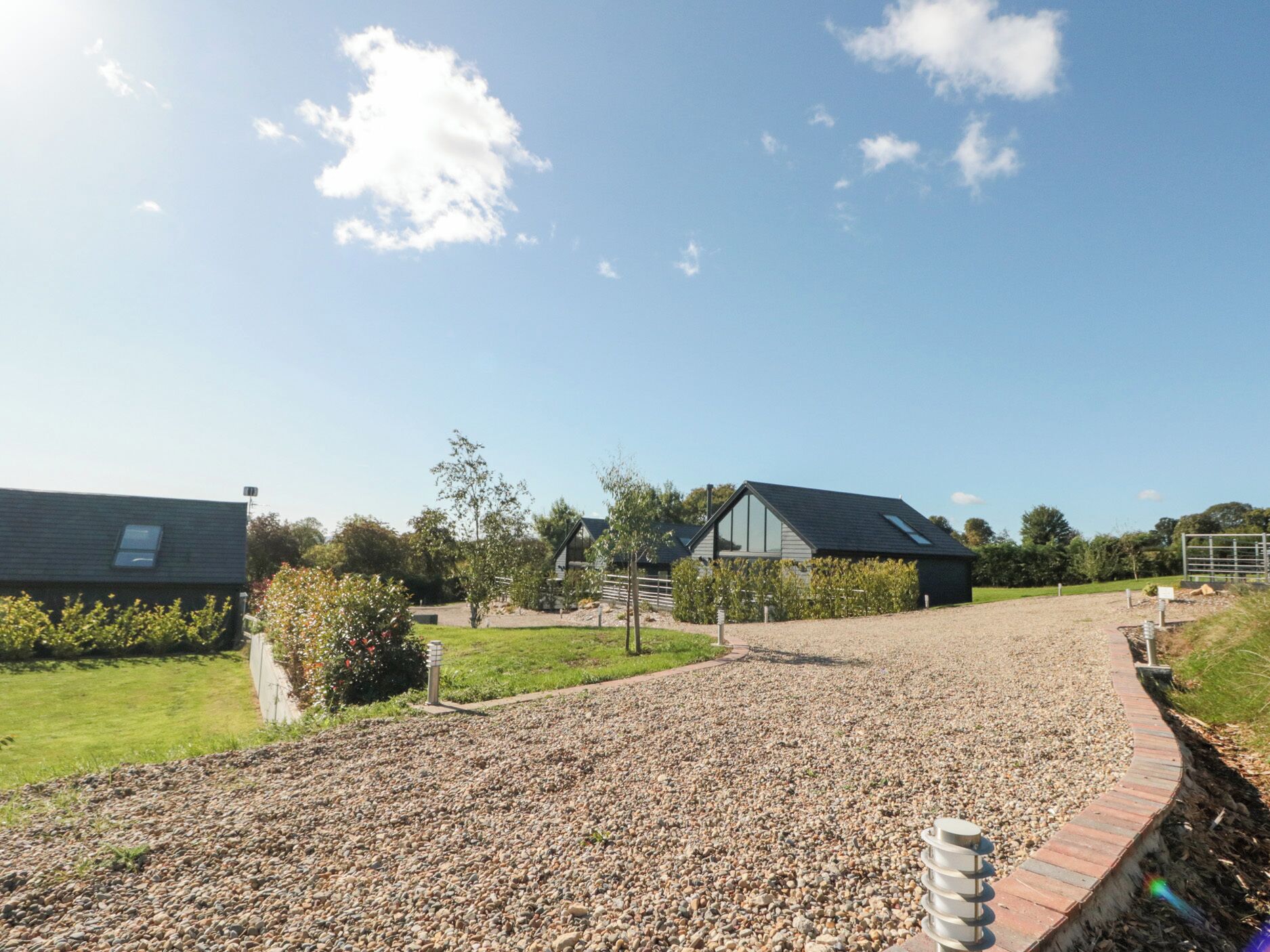 A gravel driveway leading to a modern building with a sloped roof and large windows.