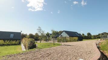 A gravel driveway leading to a modern building with a sloped roof and large windows.