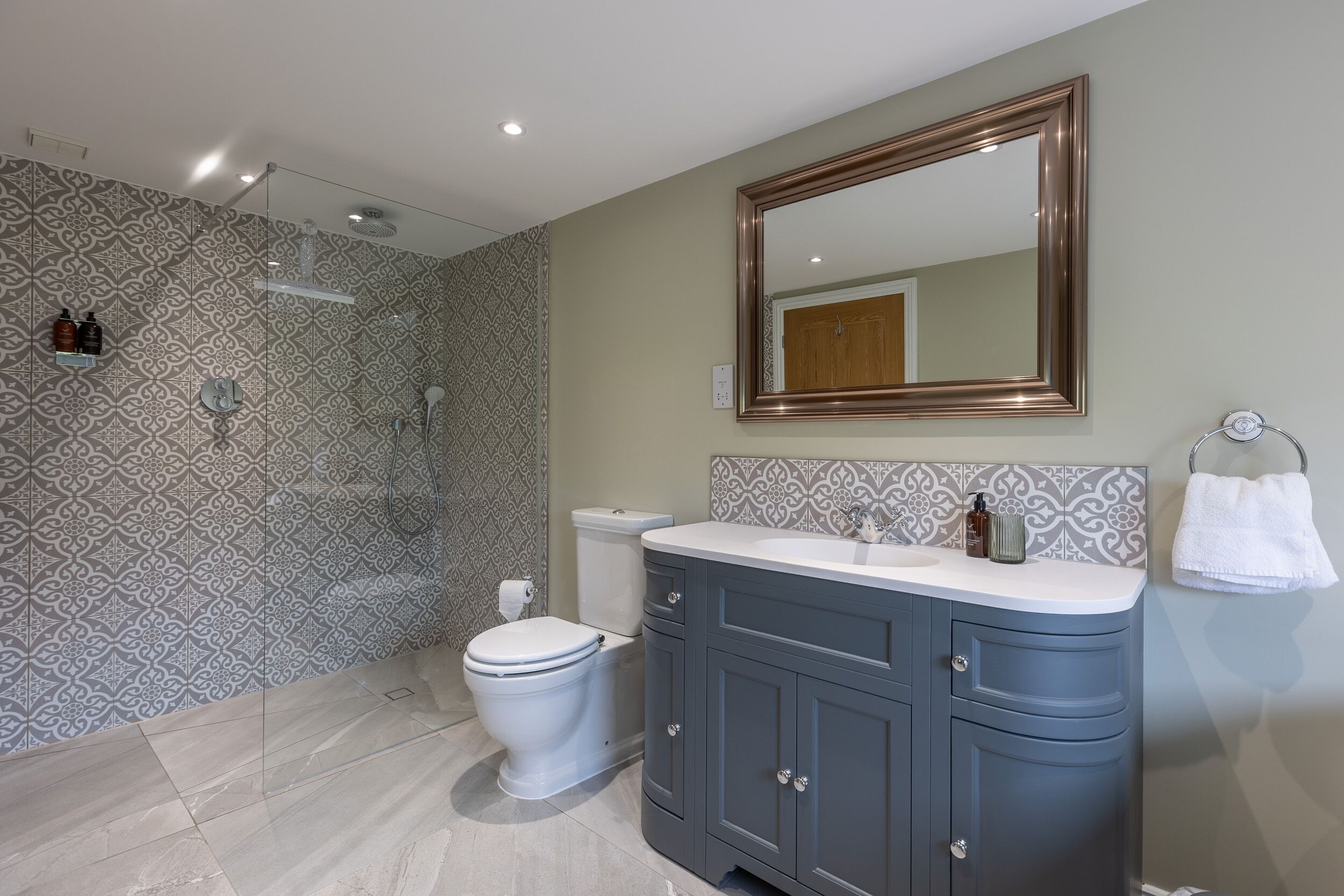 A modern bathroom with a shower, toilet, vanity, and a large mirror.