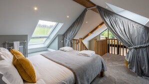 A bedroom with a skylight, a bed with pillows, a window, and a balcony with curtains. - Eagles Peak (Pickering)