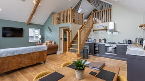 A spacious living area with a loft bedroom, wooden staircase, and a modern kitchen. - Eagles Peak (Pickering)