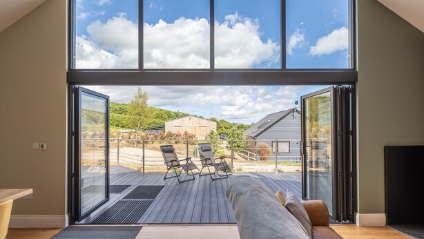 A spacious living room with a large sliding glass door leading to an outdoor deck. - Eagles Peak (Pickering)
