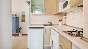 A compact kitchen with a refrigerator, washing machine, microwave, and gas stove. - 1BR Apartment - Downtown Lisbon - Chiado (Lisbon)