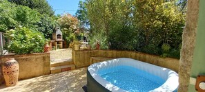 A backyard with a hot tub, a decorative fountain, and a small garden area. - Whole cozy country cottage in South of France. (Frausseilles)