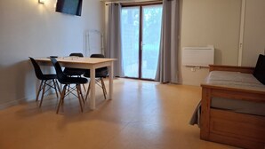 Une pièce comprenant un lit, un bureau avec des chaises, une télévision et une porte-fenêtre coulissante donnant sur l’extérieur.