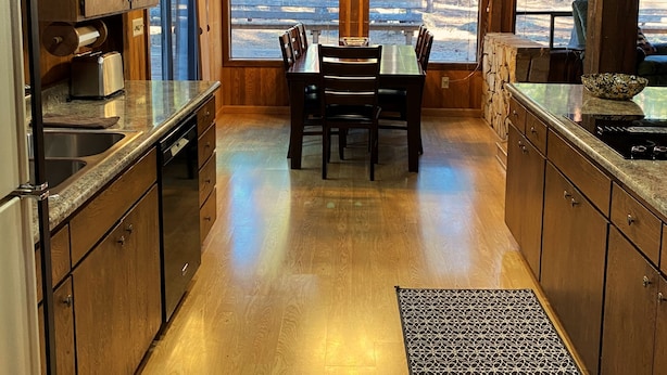 A modern kitchen with wooden cabinets, a dining table, and large windows offering a view of the outdoors. - RR18 National Forest Views! (Black Butte Ranch)
