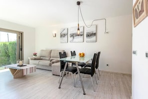 A modern dining area with a glass table, black chairs, and a minimalist design.