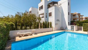 Un bâtiment moderne doté d’une piscine, d’une façade blanche et de balcons.