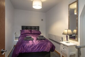 A bedroom with a bed, a bedside table, a lamp, and a mirror. - Unique Space 😍Stunning Church Conversion (Blackpool)