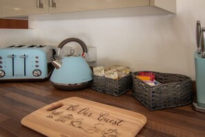 A kitchen with a blue kettle, two vintage toasters, and baskets containing food items. - Unique Space 😍Stunning Church Conversion (Blackpool)