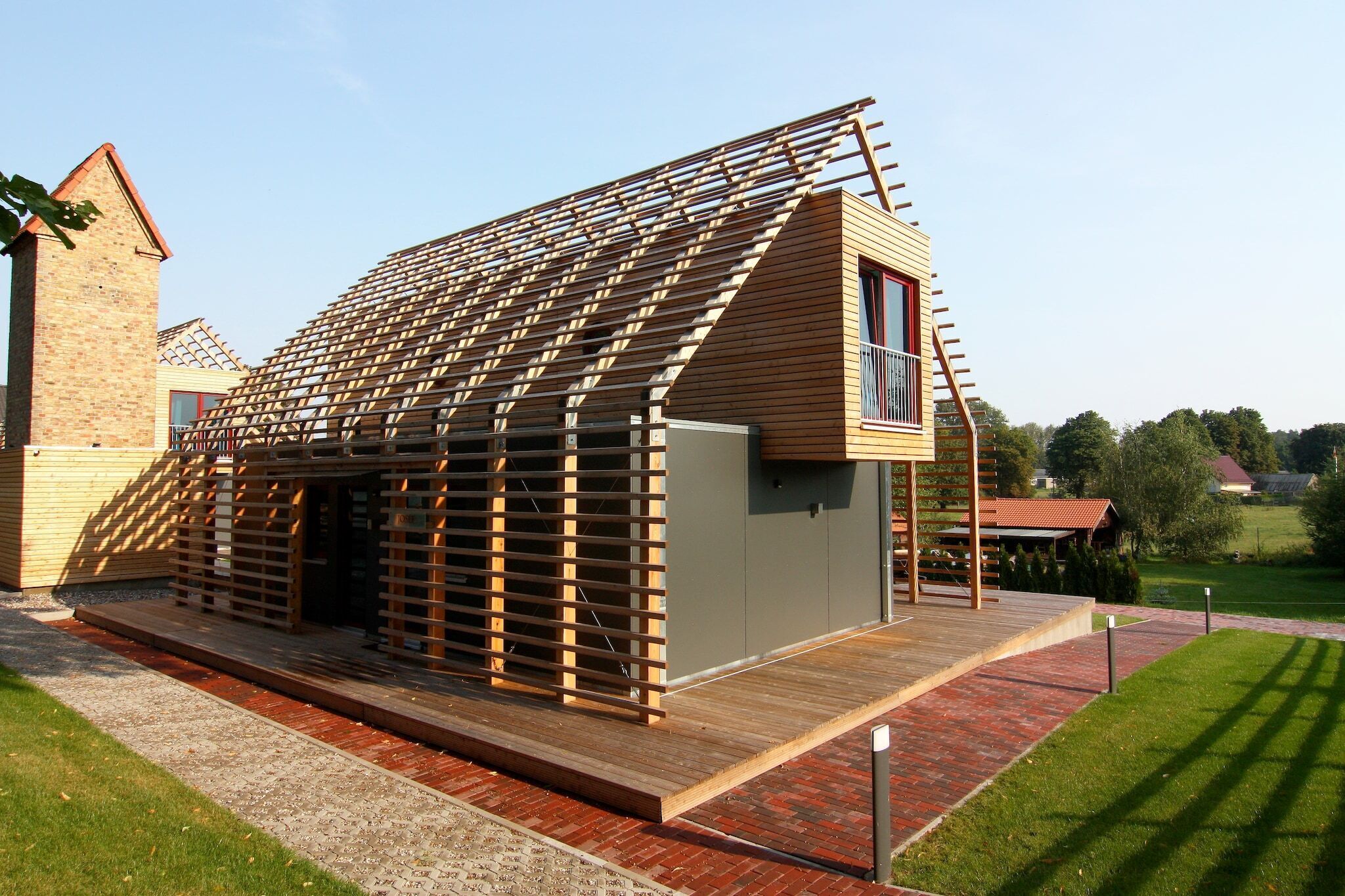 A modern house with a sloped roof, wooden exterior, and a small balcony.