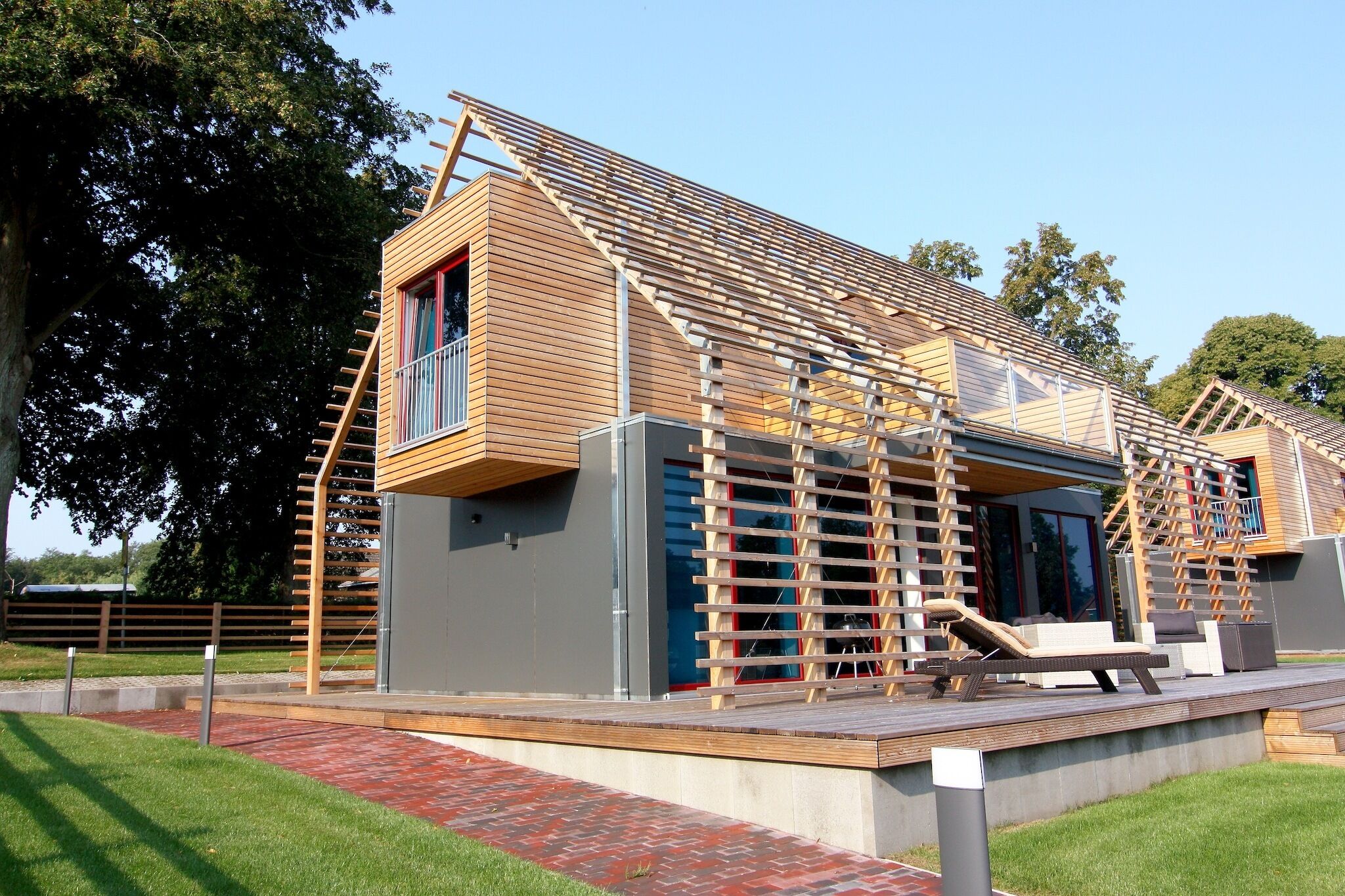A modern building with a wooden exterior, a balcony, and a staircase leading to the upper floor.