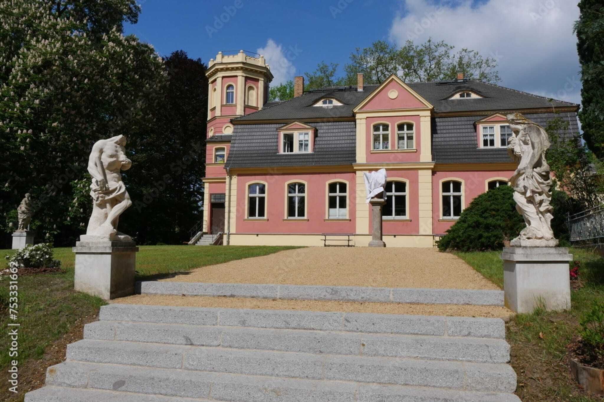A stately building with a symmetrical facade, a central entrance, and a tower on the left.