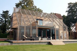 Une maison moderne avec un toit en pente, de grandes fenêtres et une façade en bois.