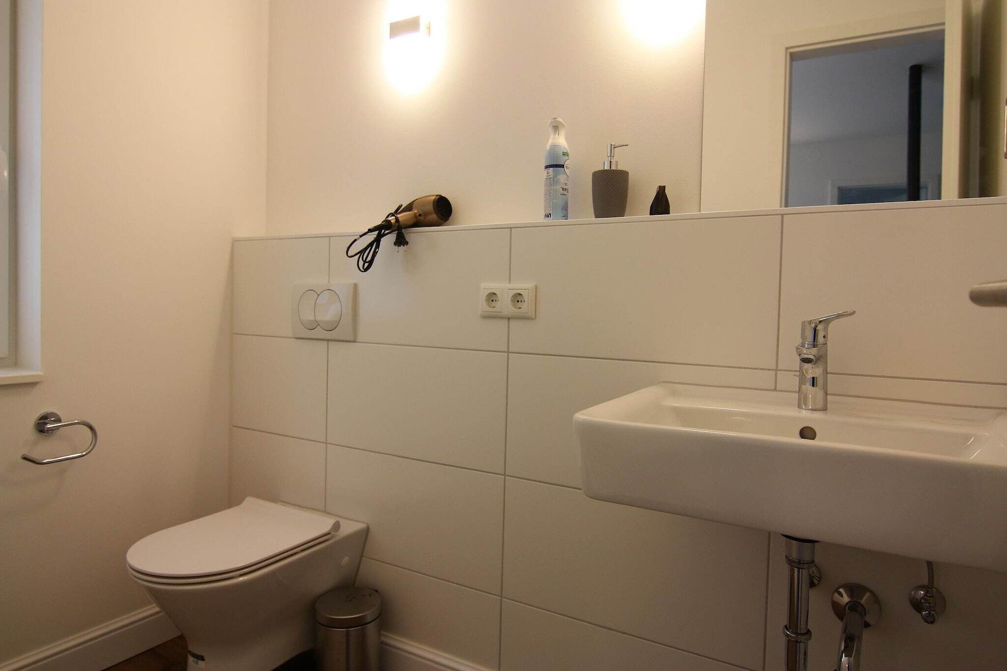 A bathroom with a toilet, sink, and a hairdryer on the wall.