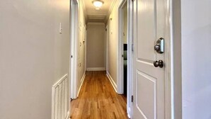 Un couloir étroit avec un plancher en bois et des murs blancs.